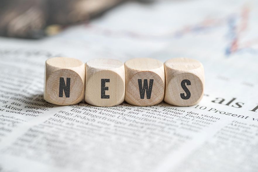 Würfel mit dem Wort "news" auf einer Zeitung