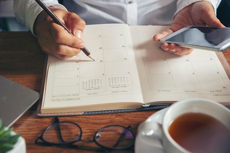 Female'hand of planner writing daily appointment.